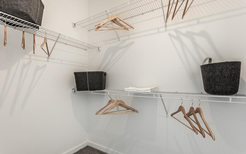 a bedroom closet with hangers and baskets
