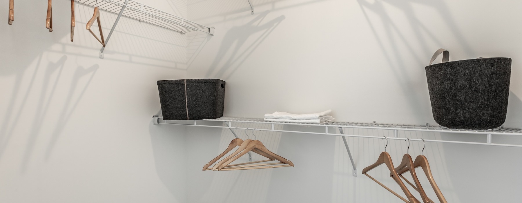 a bedroom closet with hangers and baskets